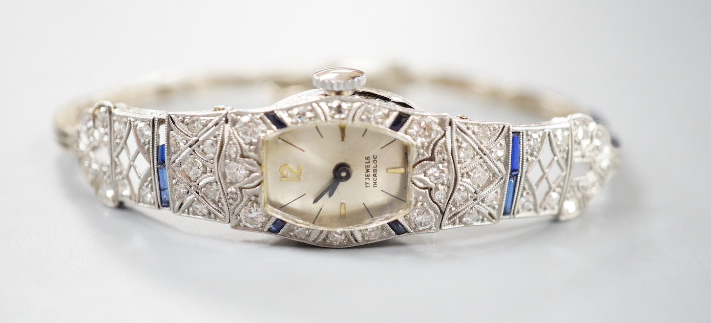 A lady's mid 20th century white metal, sapphire and diamond cluster set cocktail watch, on a 9ct bracelet (a.f.), gross weight 17.2 grams.